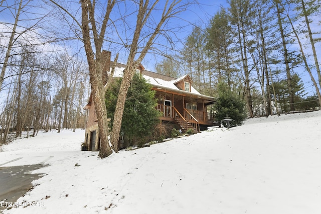 view of snow covered exterior with covered porch and a garage