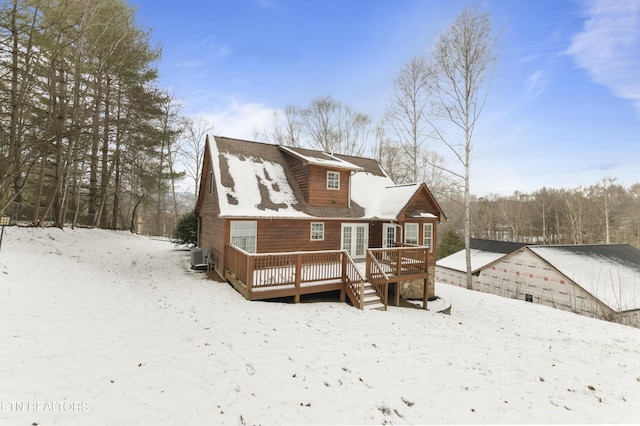 snow covered back of property with a deck