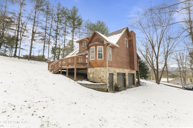 view of snowy exterior with a garage and a wooden deck