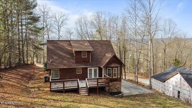 rear view of house with a deck and a wooded view