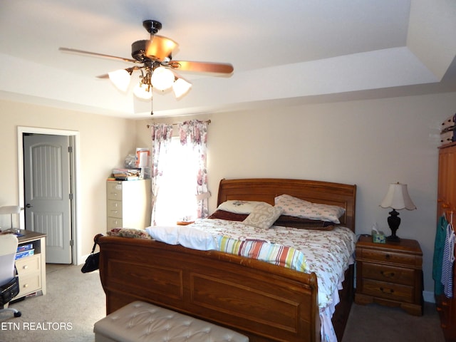 carpeted bedroom featuring ceiling fan and a tray ceiling