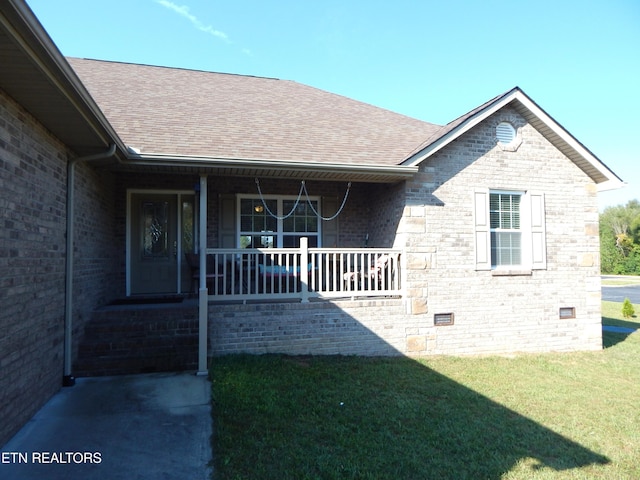 entrance to property featuring a porch and a lawn