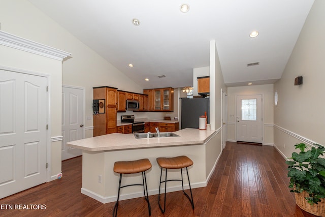 kitchen featuring kitchen peninsula, sink, appliances with stainless steel finishes, a kitchen breakfast bar, and dark wood-type flooring