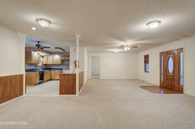 kitchen featuring beverage cooler, crown molding, kitchen peninsula, wooden walls, and a textured ceiling