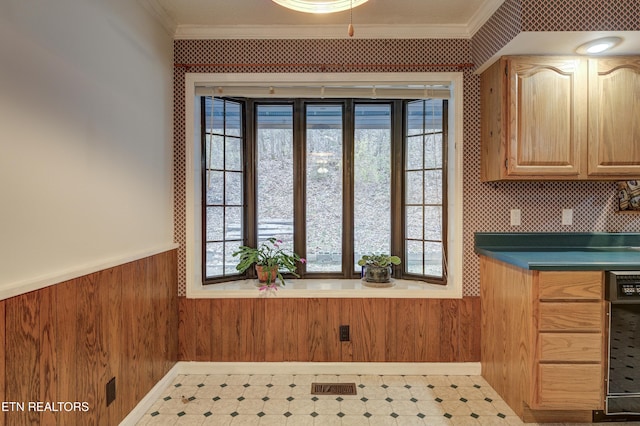 kitchen with light brown cabinets, wood walls, and crown molding