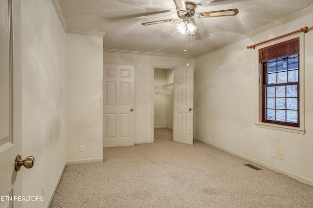 unfurnished bedroom featuring a textured ceiling, light colored carpet, ceiling fan, and crown molding