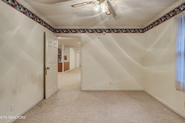 carpeted spare room featuring a textured ceiling, ceiling fan, and crown molding