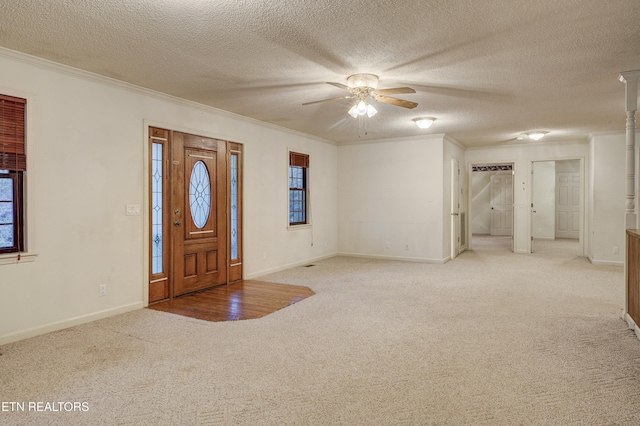 carpeted entryway with a textured ceiling, ceiling fan, and ornamental molding