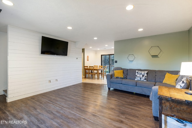 living room with dark hardwood / wood-style flooring and wooden walls