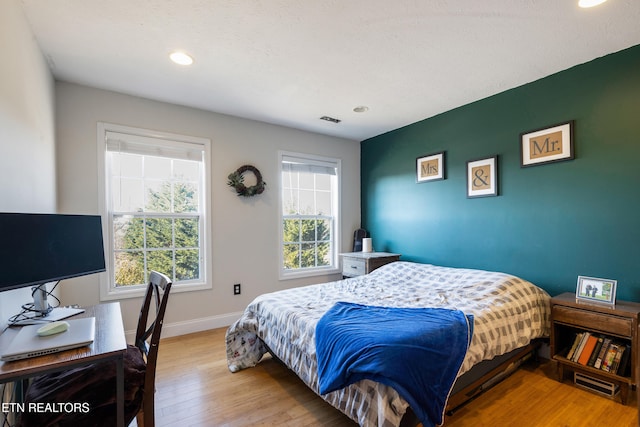 bedroom with a textured ceiling and light hardwood / wood-style flooring