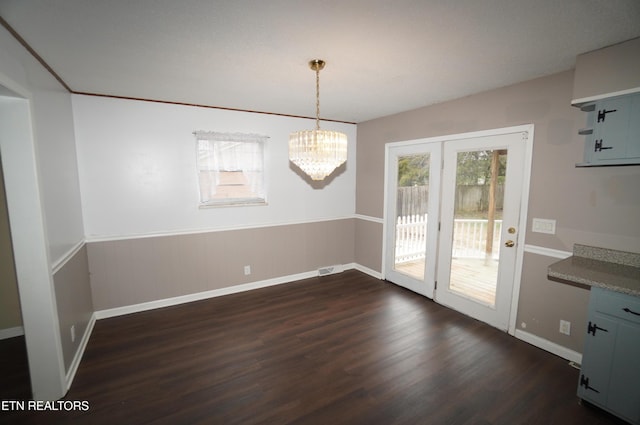 unfurnished dining area with an inviting chandelier and dark hardwood / wood-style flooring