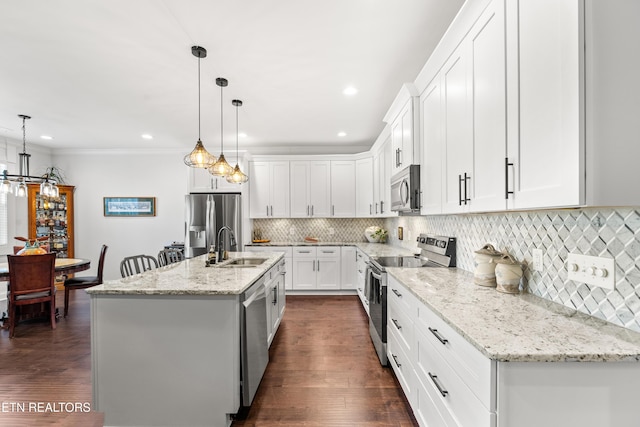 kitchen with white cabinetry, appliances with stainless steel finishes, decorative light fixtures, and an island with sink