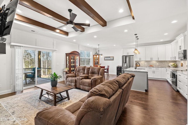 living room featuring sink, dark wood-type flooring, plenty of natural light, and beamed ceiling