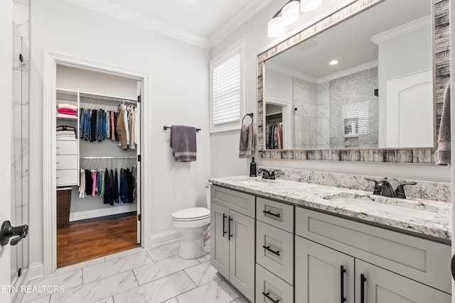 bathroom featuring a tile shower, vanity, ornamental molding, and toilet