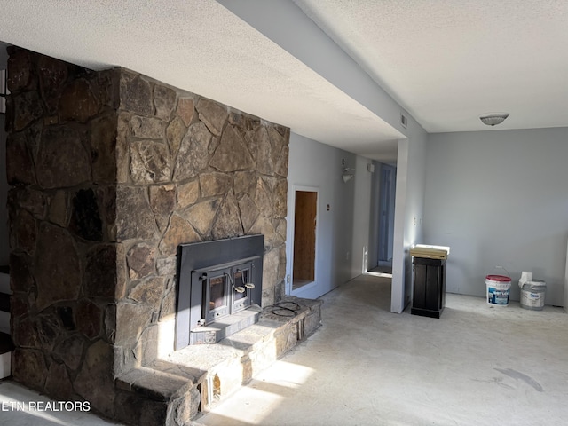 living room featuring a textured ceiling, concrete flooring, and a stone fireplace