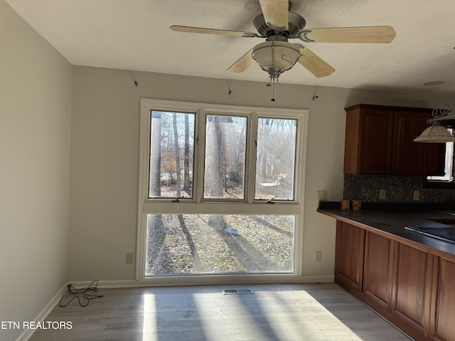 kitchen featuring light wood-type flooring, ceiling fan, a textured ceiling, and tasteful backsplash