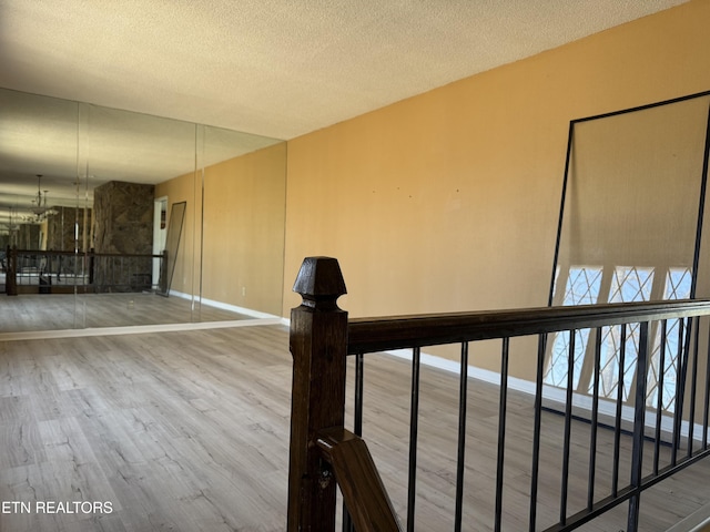 hall with a textured ceiling, baseboards, and wood finished floors