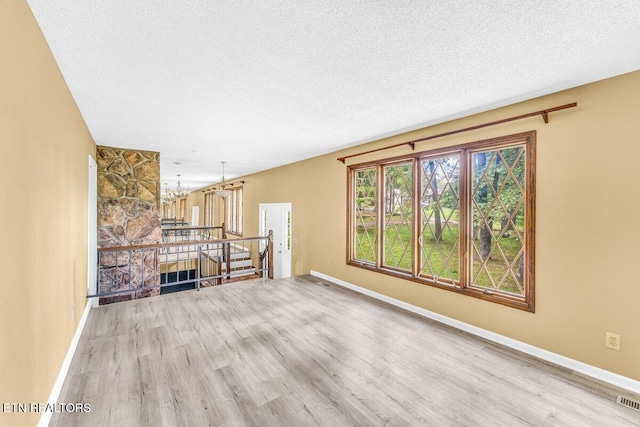 8305 Sharp Rd, Powell, TN 37849 - unfurnished living room featuring wood finished floors, a textured ceiling, baseboards, and a chandelier