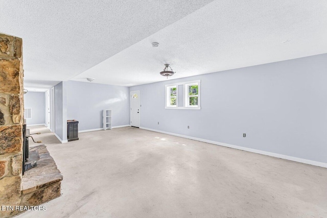 8305 Sharp Rd, Powell, TN 37849 - unfurnished living room featuring a wood stove, a textured ceiling, concrete flooring, and baseboards