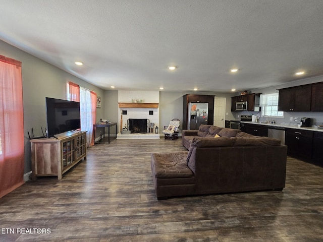 living room with dark wood-type flooring, a brick fireplace, and sink