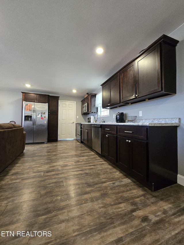 kitchen featuring sink, dark brown cabinetry, dark wood-type flooring, a textured ceiling, and stainless steel appliances