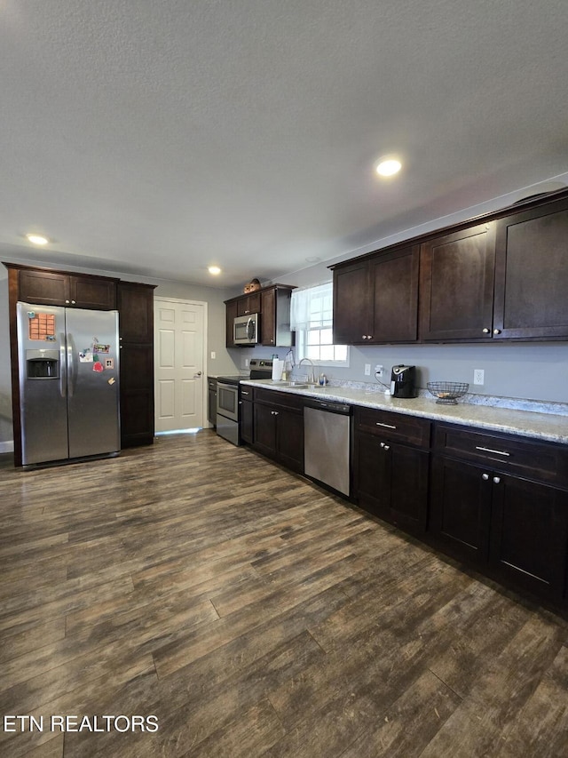 kitchen with dark brown cabinets, sink, appliances with stainless steel finishes, a textured ceiling, and dark hardwood / wood-style flooring