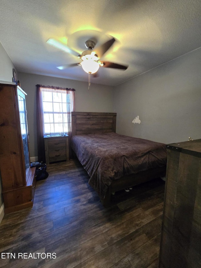 bedroom with a textured ceiling, ceiling fan, and dark hardwood / wood-style floors