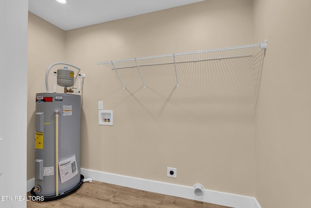 laundry area with water heater, electric dryer hookup, washer hookup, baseboards, and light wood-style floors