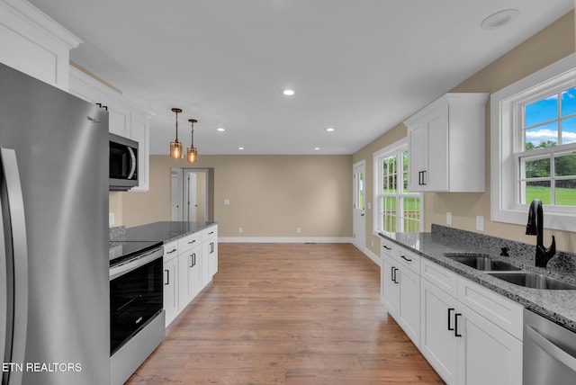 kitchen with stainless steel appliances, a sink, recessed lighting, light wood-type flooring, and white cabinets