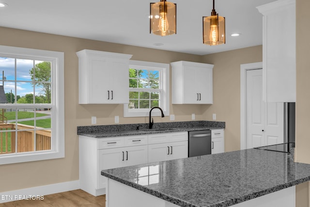 kitchen with dishwasher, a sink, baseboards, white cabinets, and dark stone counters