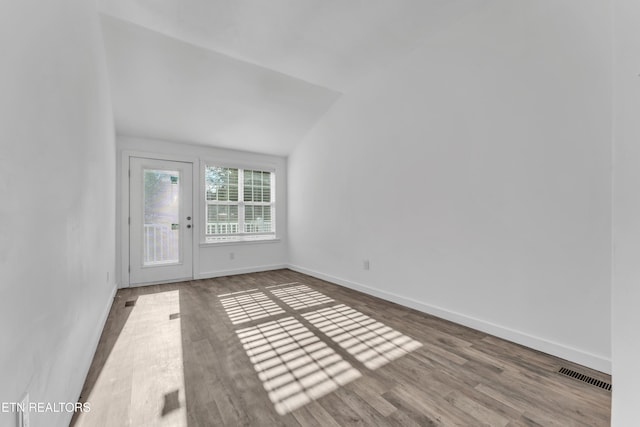 empty room featuring lofted ceiling and wood-type flooring