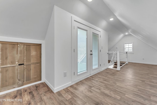 additional living space with french doors, vaulted ceiling, and wood-type flooring