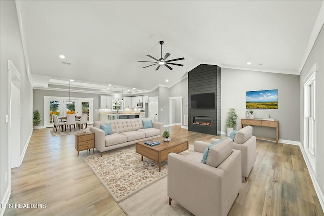 living room with lofted ceiling, a fireplace, a healthy amount of sunlight, and light hardwood / wood-style flooring