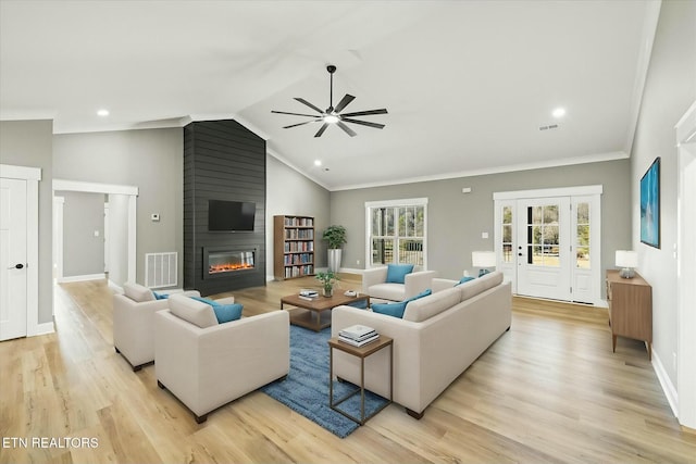 living room with crown molding, a fireplace, vaulted ceiling, and light hardwood / wood-style flooring