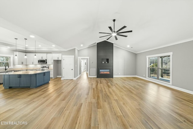 unfurnished living room with ceiling fan, a healthy amount of sunlight, a fireplace, and lofted ceiling