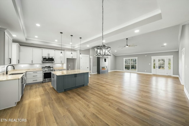 kitchen with sink, white cabinetry, a center island, hanging light fixtures, and appliances with stainless steel finishes