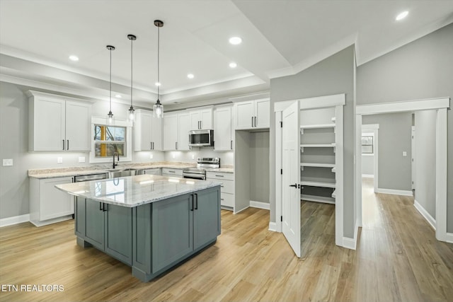 kitchen with a center island, hanging light fixtures, a tray ceiling, stainless steel appliances, and white cabinets