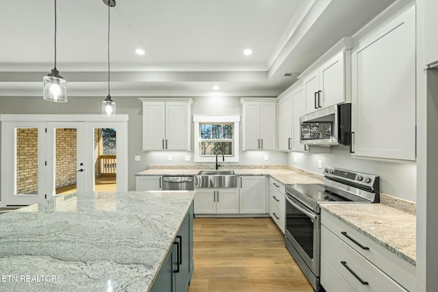 kitchen with pendant lighting, a tray ceiling, stainless steel appliances, and white cabinets