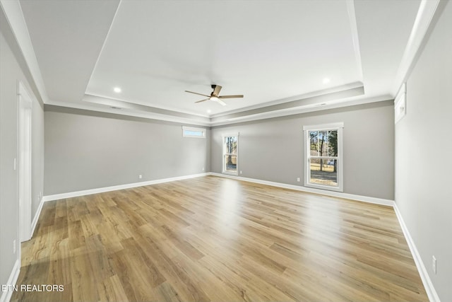 unfurnished room featuring light hardwood / wood-style floors, a raised ceiling, and ceiling fan