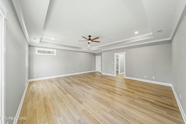 empty room featuring crown molding, ceiling fan, a raised ceiling, and light hardwood / wood-style flooring