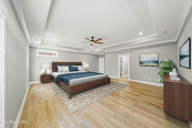 bedroom featuring a raised ceiling, ornamental molding, ceiling fan, and light hardwood / wood-style floors