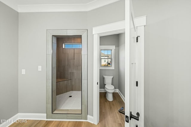 bathroom featuring toilet, hardwood / wood-style floors, and a tile shower