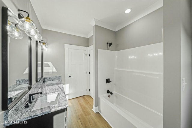 bathroom with hardwood / wood-style flooring, vanity, crown molding, and washtub / shower combination