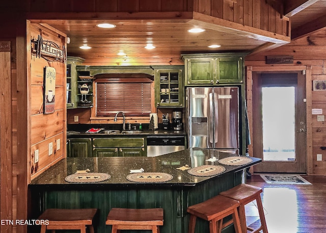 kitchen with stainless steel appliances, wood walls, a breakfast bar, wooden ceiling, and sink