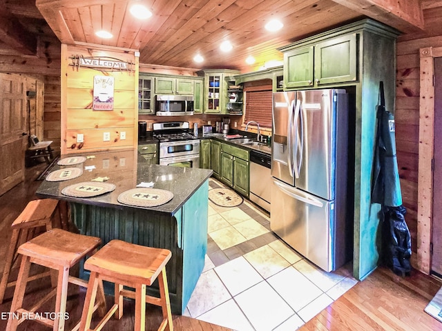 kitchen featuring sink, green cabinetry, wooden walls, wood ceiling, and appliances with stainless steel finishes