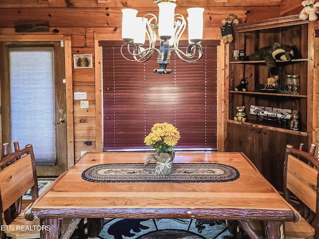 dining space with wood walls and a chandelier