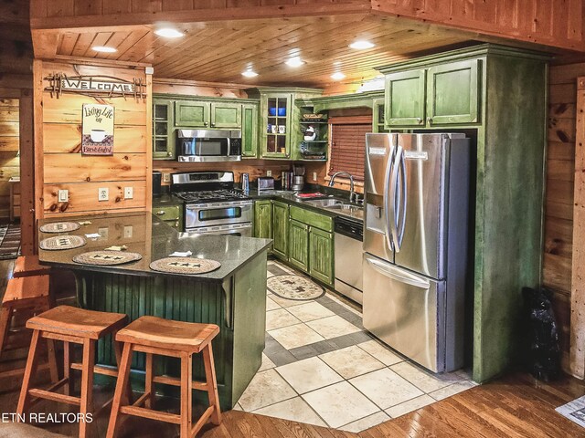 kitchen with green cabinets, wood walls, appliances with stainless steel finishes, wooden ceiling, and sink