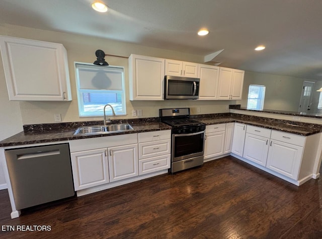 kitchen with dark wood-style floors, stainless steel appliances, a sink, and white cabinets