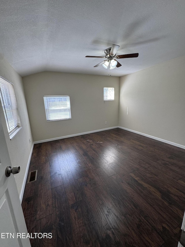 unfurnished room featuring baseboards, visible vents, dark wood finished floors, and a textured ceiling