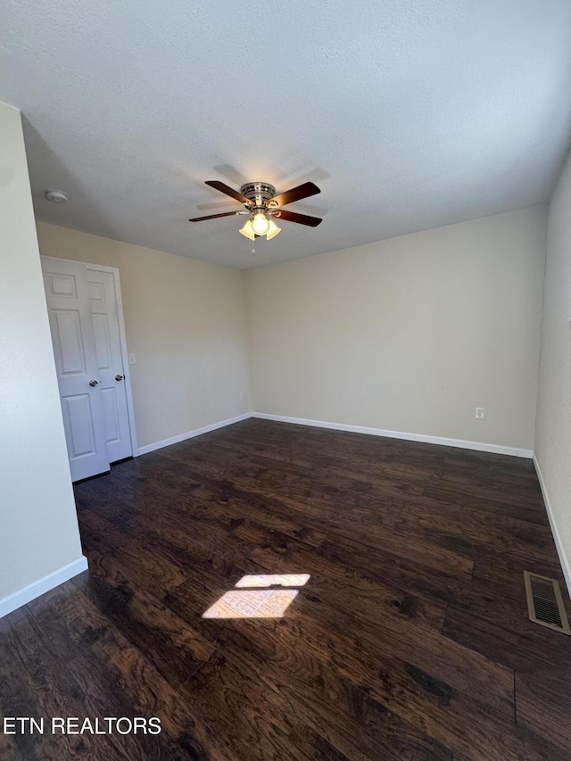 spare room with ceiling fan, a textured ceiling, wood finished floors, visible vents, and baseboards